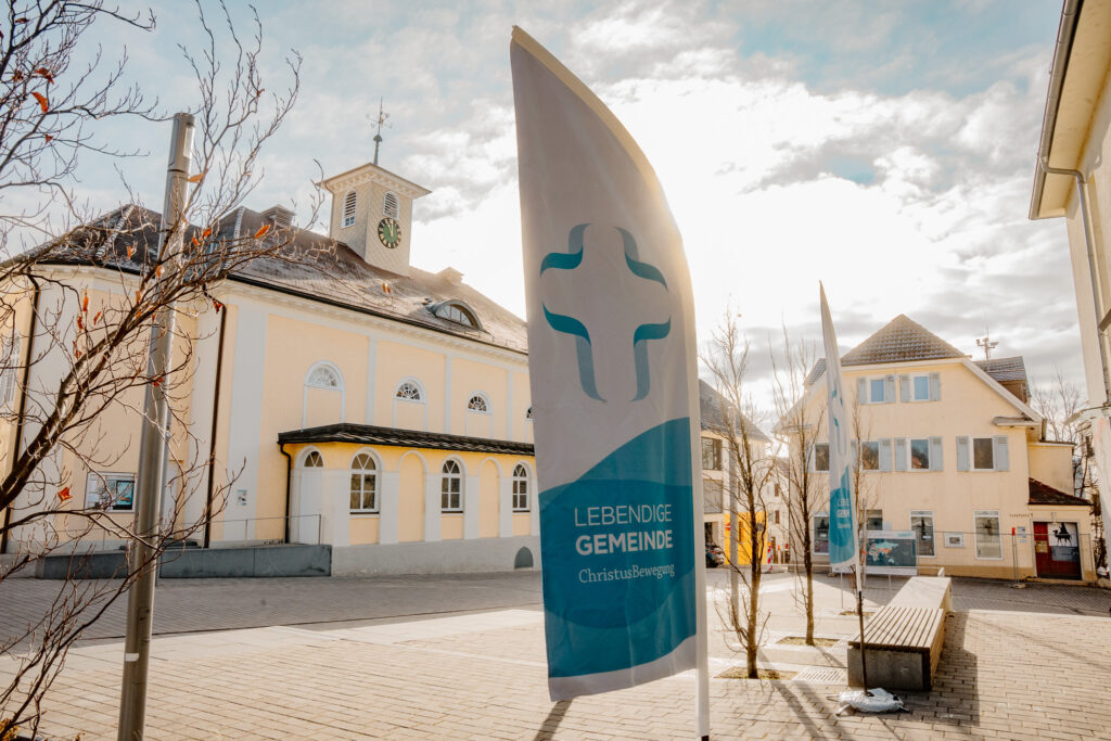 Fahne der ChristusBewegung Lebendige Gemeinde vor dem evangelischen Gemeindehaus bei Sonnenschein.